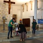 W tle ołtarza pani nachyla się do dziewczynki na wózku.Po bokach stoja nauczycielki.