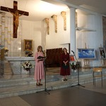 Na tle ołtarza pani czyta do mikrofonu.