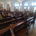 Uczestnicy przeglądu siedzą w ławkach w kościele.