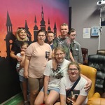 Grupa uczniów pozuje do zdjęcia na tle tapety z zamkiem.