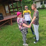 Trzy osoby stoją w kółku trzymając się za ręce.
