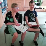 Uczniowie siedzą na krzesłach, w rękach trzymają książki do komunikacji.