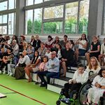 Społeczność szkolna siedząca na siedzeniach na sali gimnastycznej.