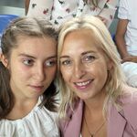 Uczennica z mamą w odświętnych strojach pozują do zdjęcia.