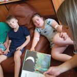 Nauczycielka czyta książkę uczniom leżącym na pufie.