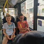 Uczniowie siedzą obok siebie na siedzeniach w autobusie.
