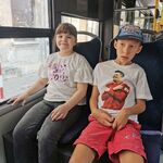 Uczeń i uczennica siedzą obok siebie na siedzeniach w autobusie.