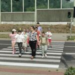 Grupa uczniów z nauczycielami przechodzi przez przejście dla pieszych z sygnalizacją świetlną.