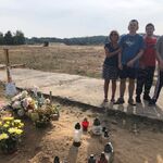 Troje uczniów i opiekun stoją przy grobie koleg.