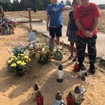 Dwoje uczniów i opiekun przy grobie kolegi.