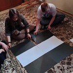 Uczeń i uczennica siedzą na dywanie i z kartek papieru układają przejście dla pieszych.
