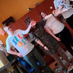 Na dywanie stoją trzy dziewczynki i jeden chłopiec. Uczniowie ćwiczą poprawne rozglądanie się podczas przechodzenia przez pasy. Uczniowie patrzą i wskazują ręka w lewa stronę.