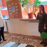 Dwie dziewczynki i dwóch chłopców stoi po jednej stronie przejścia, natomiast po drugiej stronie stoi dziewczynka i podnosi do góry kartki z kolorami sygnalizacji świetlnej.