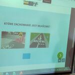 Uczeń stoi i przy tablicy multimedialnej i myśli, które zachowanie jest poprawne