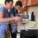 Nauczycielka pomaga uczniowi nalać ciasto na patelnię.