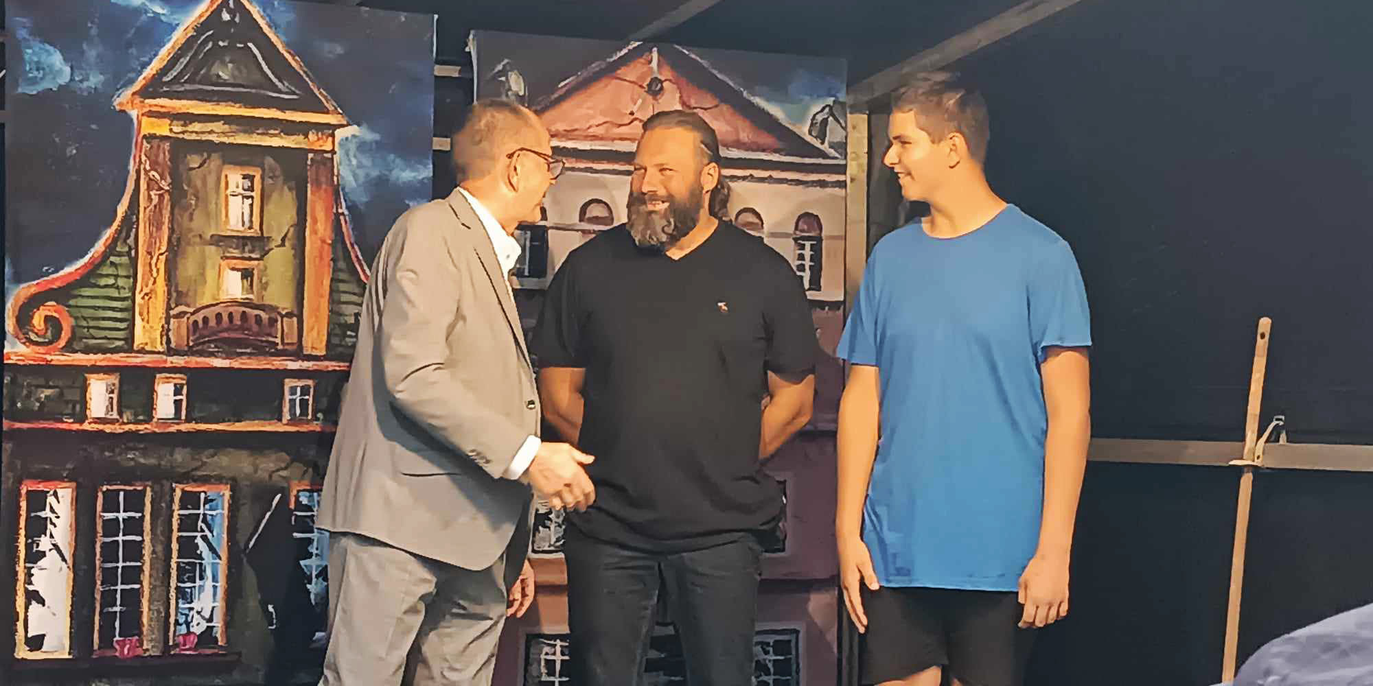Nauczyciel i uczeń odbierają nagrodę z rąk organizatora na scenie.
