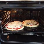 Wnętrze piekarnika z pieczącymi się pizzami.