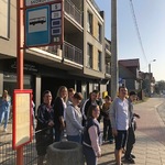 Uczniowie stoją na przystanku autobusowym.