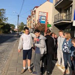 Grupa uczniów stoi na przystanku autobusowym.