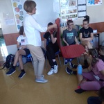 Nauczycielka prezentuje materac. Uczniowie siedzą na krzesłach
