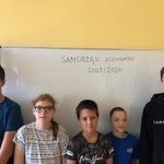 Uczniowie stoją przed białą tablicą
