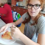 Uczennice siedzą przy stole i jedzą pieczone jabłka.