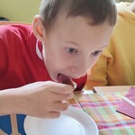 Uczeń pochylony nad talerzem  je kanapkę.