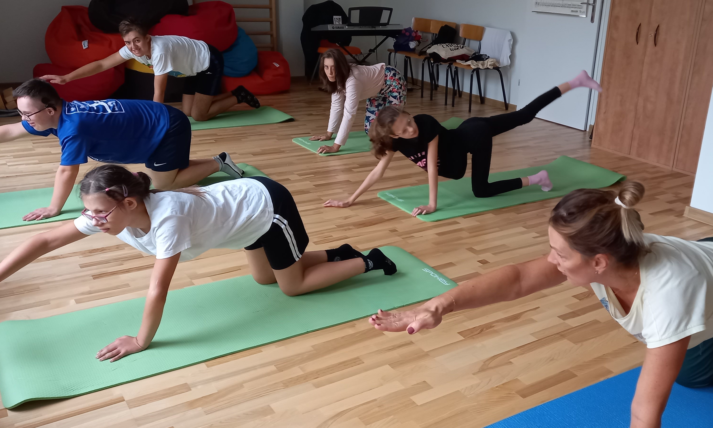 Grupa uczniów wykonuje na matach ćwiczenie.