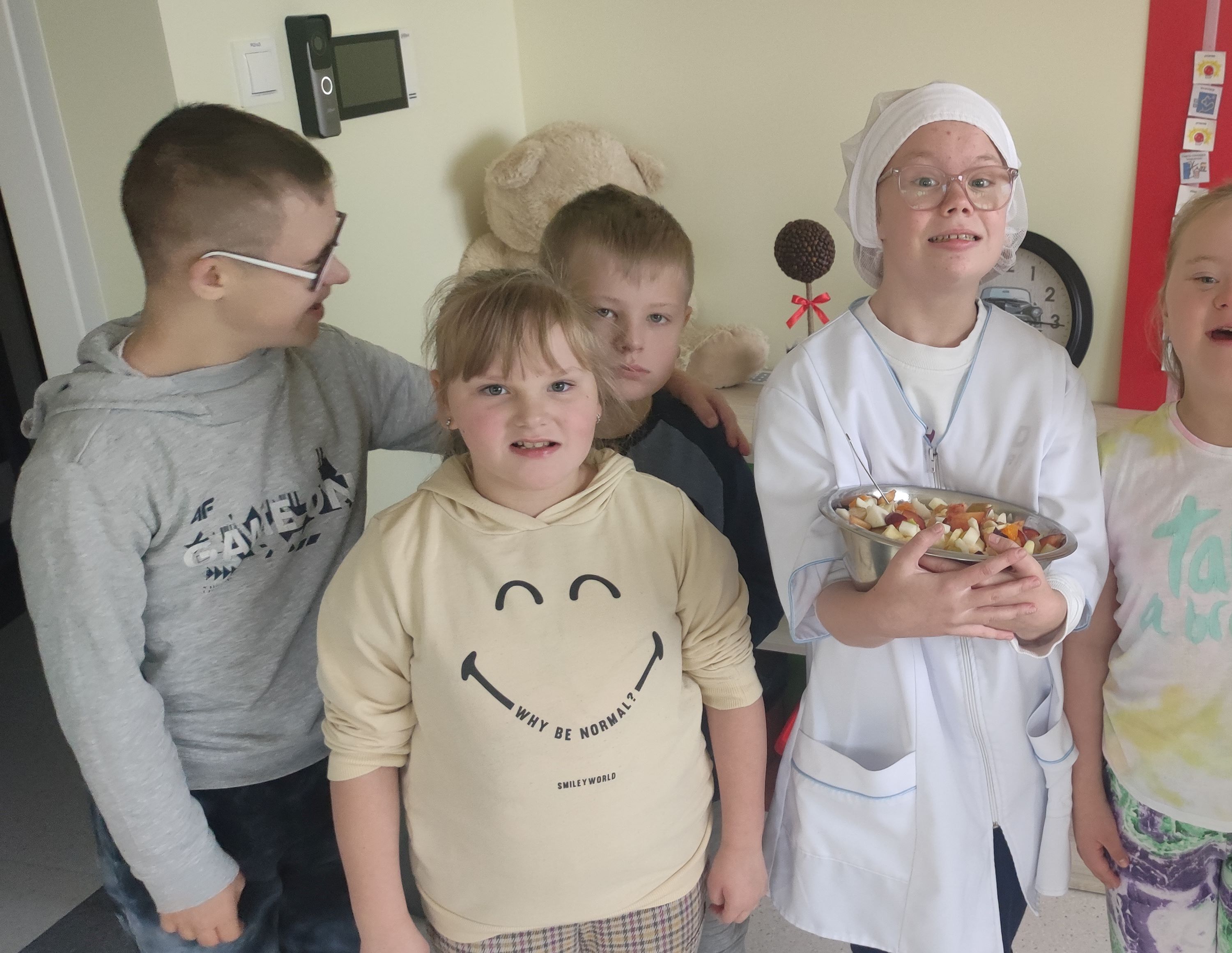 Grupa uczniów. Uczennica stojąca w środku trzyma misę z sałatką.