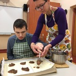 Nauczyciel i uczeń nakładają dżem na ciasto francuskie leżące na blaszce.