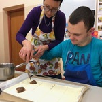 Nauczyciel i uczeń nakładają dżem na ciasto francuskie leżące na blaszce.