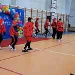Grupa uczniów w czerwonych ubraniach tańczy na sali gimnastycznej