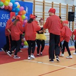 Grupa uczniów w czerwonych ubraniach tańczy na sali gimnastycznej