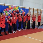 Grupa uczniów w czerwonych ubraniach tańczy na sali gimnastycznej