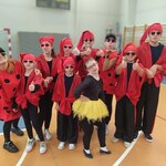 Grupa uczniów w czerwonych ubraniach pozuje na sali gimnastycznej
