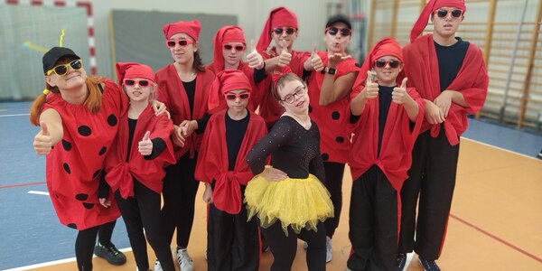 Grupa uczniów w czerwonych ubraniach pozuje na sali gimnastycznej