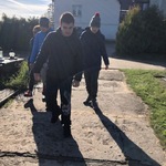Trzech uczniów i opiekun idą drogą na cmentarzu