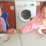 Dwie uczennice siedzą przy stole i jedzą pizzę.