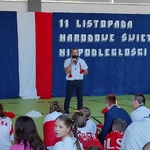 Nauczyciel prowadzący apel na tle dekoracji.