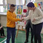 Nauczycielka wręcza nagrodę uczestnikowi konkursu.