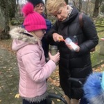 Nauczycielka zapala znicz. Obok stoi uczennica ze zniczem w ręku.
