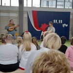 Uczniowie oglądają występ artystów grających na dawnych instrumentach.