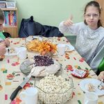 Uczniowie siedzą przy stole i jedzą urodzinowy tort.