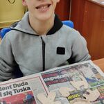 Uczeń siedzi za stołem. Przed nim leżą na gazecie figurki z gliny.