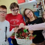 Uczniowie stoją przy ławce. W ręku trzymają ułożona przez siebie w koszyku jesienna kompozycję z darów jesieni.