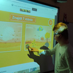 Uczeń na tablicy multimedialnej rozwiązuje quiz o jesieni.
