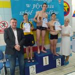 Zawodnicy na podium oraz organizatorzy zawodów pływackich.