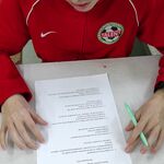 Uczeń siedzi przy stole i rozwiązuje test.