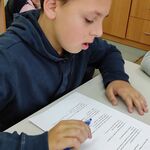 Uczeń siedzi przy stole i rozwiązuje test.