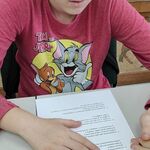 Uczennica siedzi przy stole i rozwiązuje test.